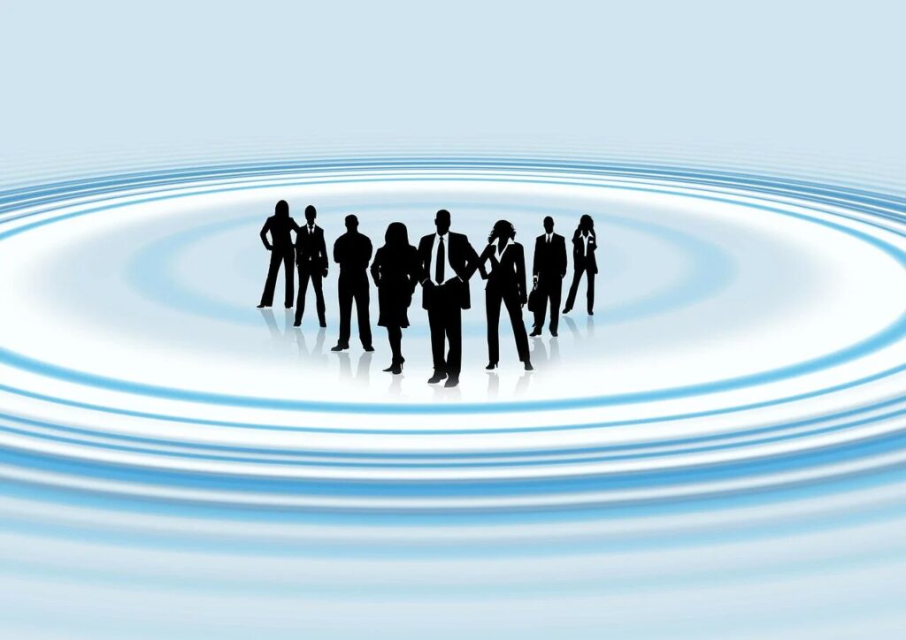 波紋の広がる円の中心に立つ、人々のシルエットのイメージ
